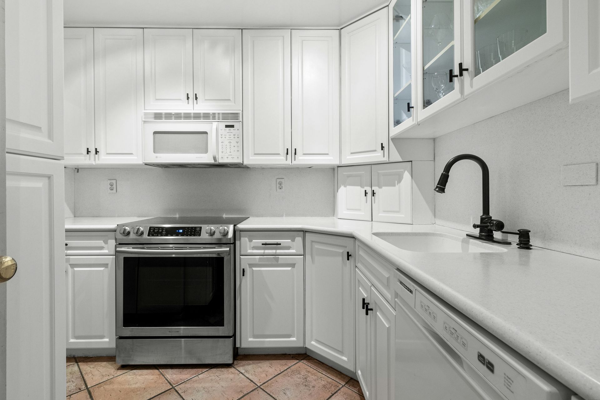 A kitchen with white cabinets and a silver stove top oven